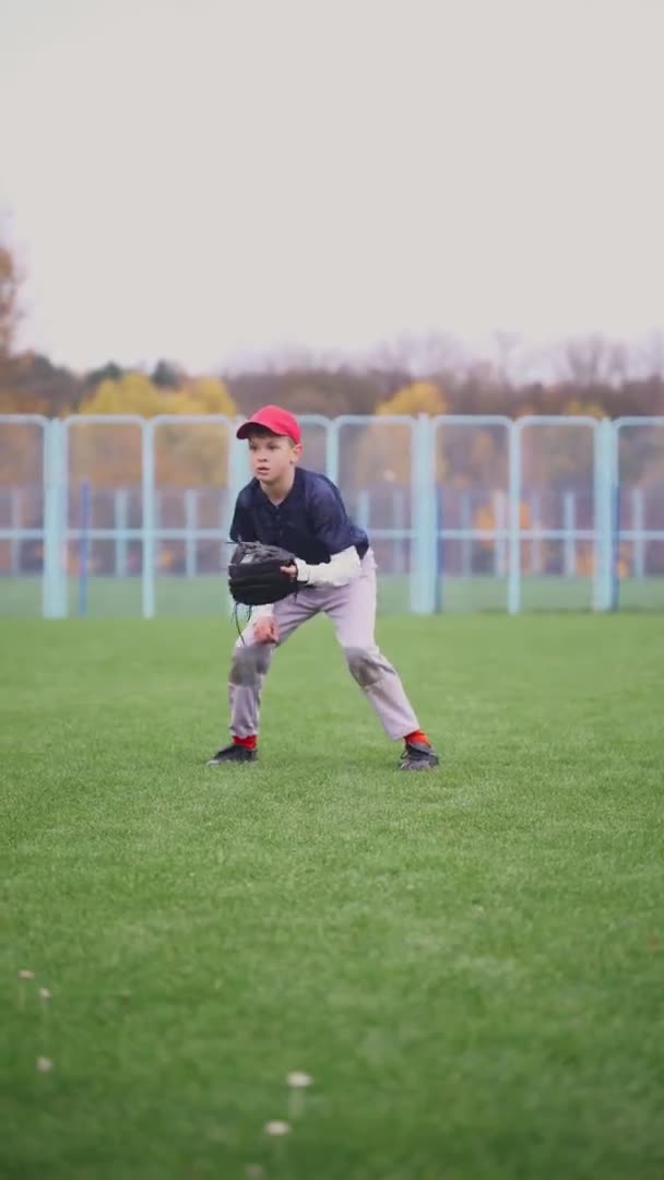 Бейсбольний турнір в школі, хлопчик пітчер біжить і успішно ловить швидку кулю в рукавичці, відправляє перепустку іншому гравцеві, 4k Вертикальне відео . — стокове відео