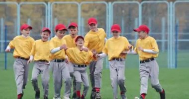 Okulda beyzbol, sarı üniformalı beysbol oyuncularından oluşan bir takım zaferle, başarılı oyunla, olumlu duygularla, 4k Slow Motion 'la kucaklaşıyor ve seviniyor..