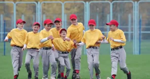 Baseball ve škole, tým kluků baseballových hráčů ve žlutých uniformách dostat objetí a raduje se z vítězství, úspěšná hra, pozitivní emoce, 4k pomalý pohyb. — Stock video