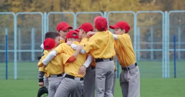 Baseball ve škole, tým kluků baseballových hráčů ve žlutých uniformách dostat objetí a raduje se z vítězství, úspěšná hra, pozitivní emoce, 4k pomalý pohyb. — Stock video