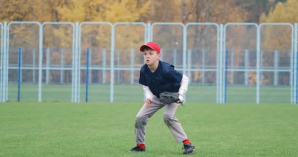 Turniej baseballowy w szkole, miotacz chłopiec łapie szybką piłkę w rękawicy i wysyła przepustkę do innego gracza, 4k slow motion.. — Wideo stockowe