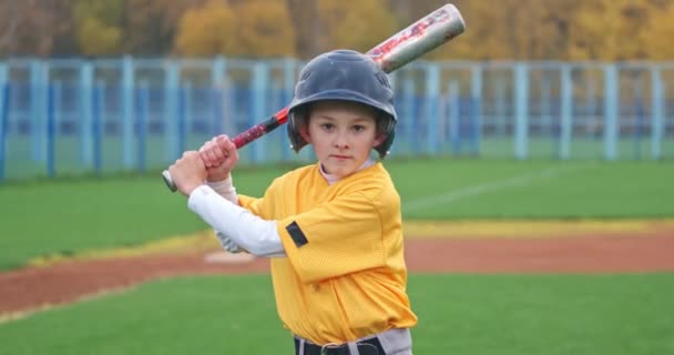 Porträtt av en pojke basebollspelare på en suddig bakgrund, smeten håller ett basebollträ i sina händer och tittar på kameran, 4k 50fps. — Stockvideo
