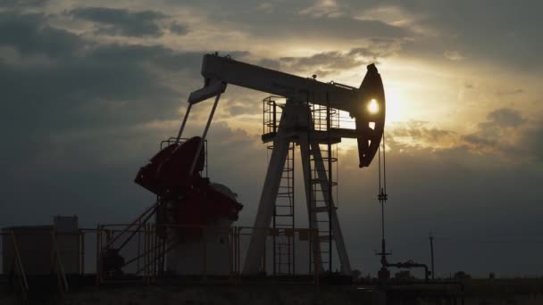 Minería de petróleo, una plataforma petrolífera en el campo bombea petróleo, vista de una plataforma petrolífera al atardecer, extracción de recursos para la producción de combustible, luz del atardecer en la hora dorada, timelapse. — Vídeo de stock