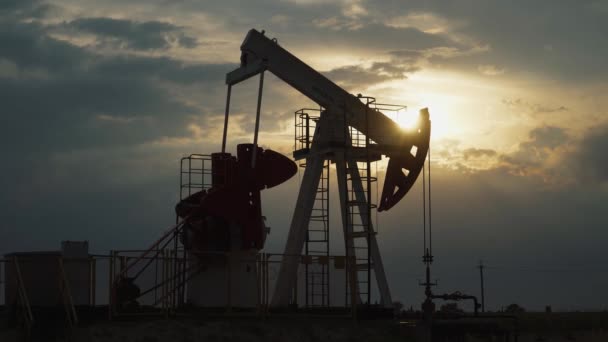 Petrol madenciliği, tarladaki bir petrol kulesi petrol pompalıyor, gün batımında bir petrol kulesi manzarası, yakıt üretimi için kaynak çıkarma, altın saatinde gün batımı ışığı. — Stok video