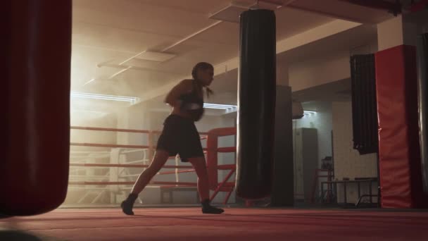 Kickboxing, γυναίκα μαχητής εκπαιδεύει γροθιές του, χτυπάει ένα σάκο του μποξ, ημέρα κατάρτισης στο γυμναστήριο πυγμαχίας, δύναμη ταιριάζει σώμα, το κορίτσι χτυπά γρήγορα. — Αρχείο Βίντεο