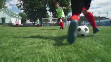 Bir grup genç erkek futbol oynuyor, futbol sahasında antrenman yapıyor, çocuk gol atıyor..