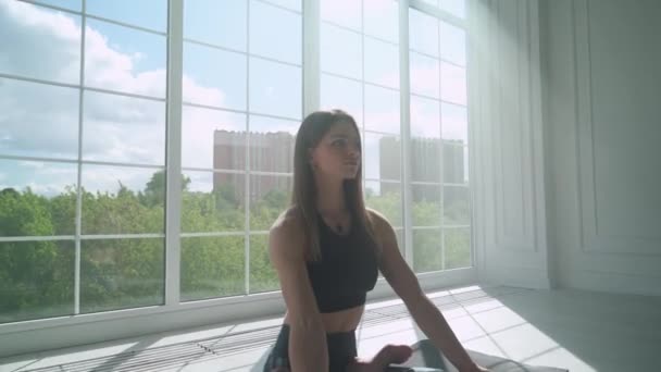 Здоровье, молодая женщина медитирует и занимается йогой, спокойное настроение, расслабляясь в заполненной светом белой комнате, девушка сидит на полу. — стоковое видео