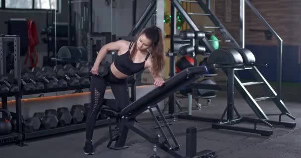 Young Female in the Gym, girl lifts a dumbbell in a tilt, muscle training with weights, 4k 50fps. — Vídeo de Stock