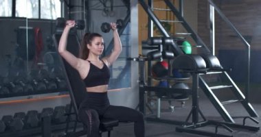 Spor salonunda genç bir bayan antrenman yapıyor, kız halteri kaldırıyor, ağırlık ile kas antrenmanı yapıyor, 4 km yavaş çekim..