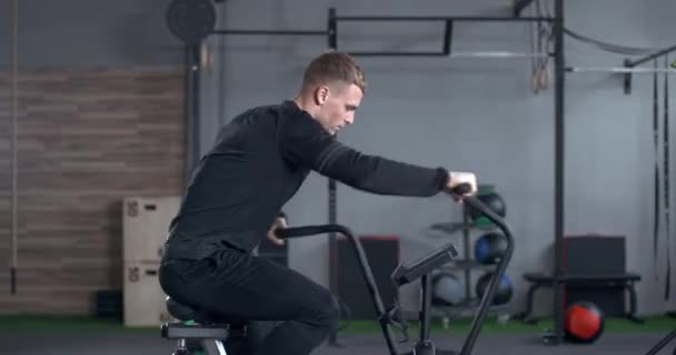 Uomo in palestra, giovane si allena su un simulatore ellittico di bici, esercizio aerobico e allenamento di resistenza. — Video Stock