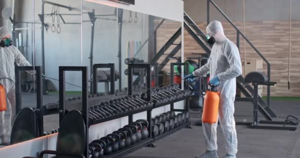 Especialista en protección química en un traje de protección maneja el espacio GYM para proteger contra la propagación del virus, el proceso de descontaminación del espacio público, Covid-19. — Vídeos de Stock