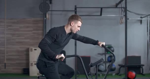 Giovane uomo si allena su un simulatore di bici ellittica, esercizio aerobico e allenamento di resistenza. — Video Stock