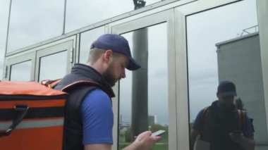 Kurye, ofise kutular içinde yiyecek getiriyor. Yemek teslimatı, iş yerindeki adam, siparişi akıllı telefondan onaylıyor..