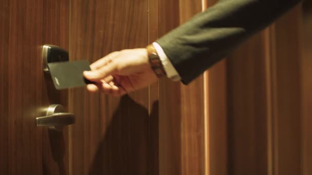 El hombre abre la puerta a la habitación del hotel, con una tarjeta de acceso NFC, check-in en el apartamento, viaje de negocios. — Vídeo de stock