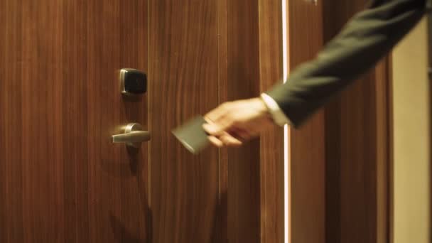 Homem de terno abre a porta para o quarto de hotel, usando um cartão-chave NFC, check-in para o apartamento, viagem de negócios. — Vídeo de Stock