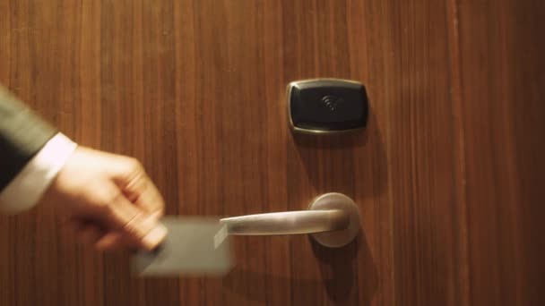 Man in pak opent de deur naar hotelkamer met een NFC-sleutelkaart, check-in bij het appartement, zakenreis. — Stockvideo
