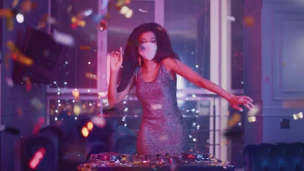 Luxus-Party, Glamour-Afrikanerin mit Schutzmaske tanzt im Nachtclub, goldenes Konfetti fliegt durch die Luft, Neonlicht, private Party während der Pandemie, 4k Zeitlupe.