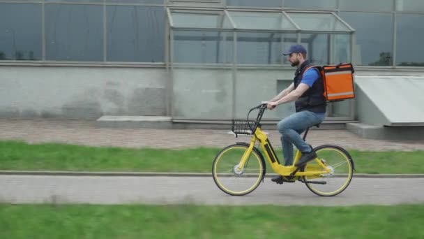 Mensajero con una bolsa monta una bicicleta para el cliente, el proceso de entrega de alimentos. — Vídeos de Stock