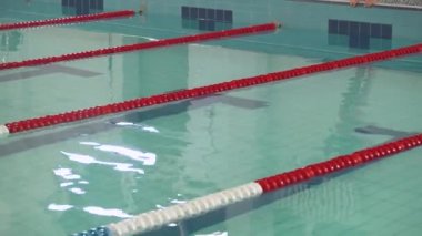 Genç profesyonel bayan yüzücü suya atlıyor ve havuzda yüzüyor, kadın suda antrenman yapıyor..