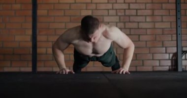 Spor salonundaki atletik adam, adam patlayıcı şınav çekiyor, ağır çekimde alkışlıyor, çapraz formda..
