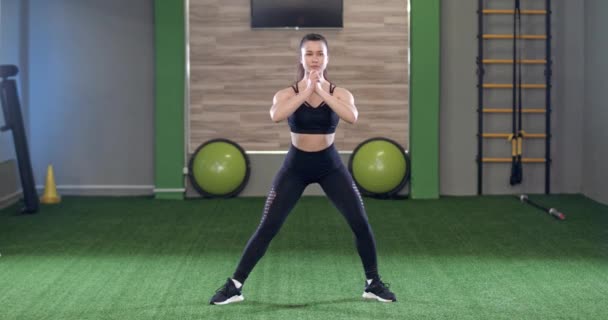 Jonge vrouw voert een warming-up in de sportschool, een fitnesscoach toont en voert oefeningen uit om de spieren op te warmen voordat u gaat trainen. — Stockvideo