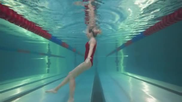 Професійна жінка плаває в басейні, молода жінка виконує елементи синхронізованого плавання, красивий танець під водою . — стокове відео