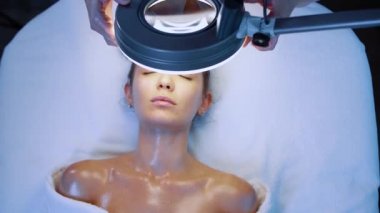 Spa ve cilt bakımı, profesyonel güzellik uzmanı lambanın ışığı altında kızlara bakar, cilt analizi.