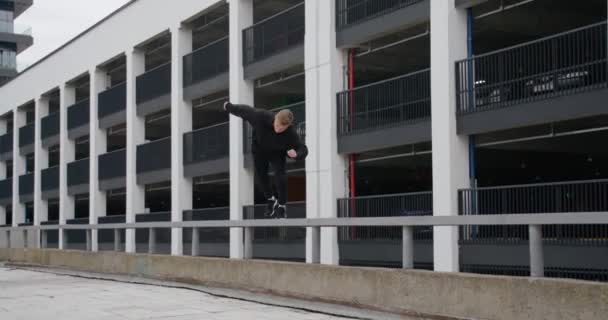 Молодой человек делает флипы и прыжки, паркур по современному городу, свободный бег в замедленной съемке. — стоковое видео