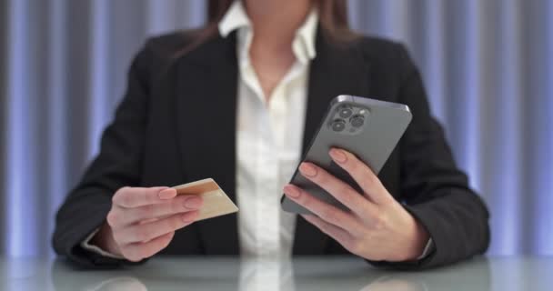 Junge Frau sitzt am Tisch und bezahlt Online-Einkäufe mit dem Smartphone, gibt Kreditkartendaten am Bildschirm ein, kauft online ein. — Stockvideo