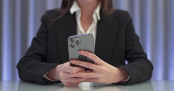 Anonieme zakenvrouw zit aan tafel en typt tekst op smartphone, communicatie op het internet. — Stockvideo