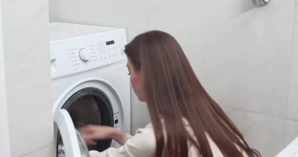 Νεαρά γυναικεία ρούχα φόρτωσης και λευκές πετσέτες στο πλυντήριο ρούχων, πλύσιμο ρούχων στο σπίτι. — Αρχείο Βίντεο