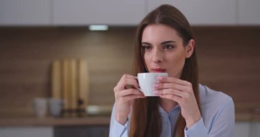 Genç ve güzel bir kız mutfakta oturuyor ve kahve içiyor, portre çekiyor, evde tatil yapıyor..