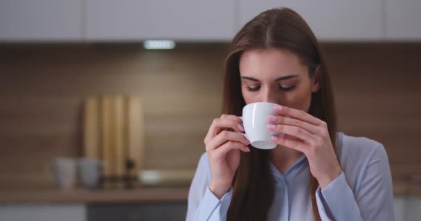 Молодая красивая женщина сидит на кухне и пьет чай, портрет, выходной на дому. — стоковое видео