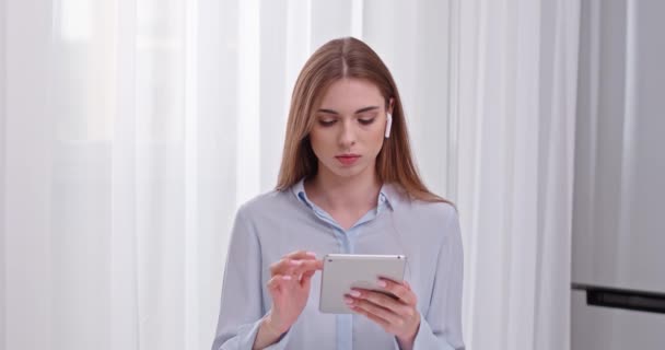 Jonge vrouw freelancer op shirt, werken met een tablet scherm, werken op afstand van huis, vrouw in draadloze hoofdtelefoon. — Stockvideo