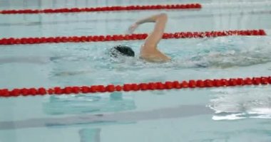 Young professional female swimmer swims in the pool, woman swimming and training in the water, slow motion.