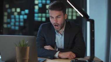 İş yerinde çok çalışan, ofis müdürü geç saatlere kadar çalışan, iş yerinde uyuyan, gece vakti esneyen bir adam..