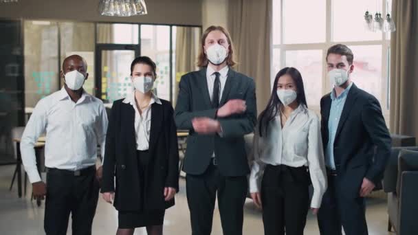 L'équipe du bureau se tient debout et regarde la caméra, les gestionnaires dans des masques médicaux de protection, travaillant dans le bureau dans le contexte de la pandémie de coronavirus, 4k au ralenti. — Video