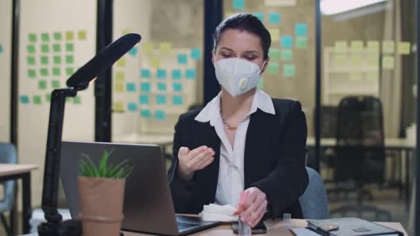 Femmina pulisce le mani e disinfetta smartphone con antisettico, il processo di disinfezione del posto di lavoro in ufficio, precauzioni durante la pandemia di coronovirus. — Video Stock