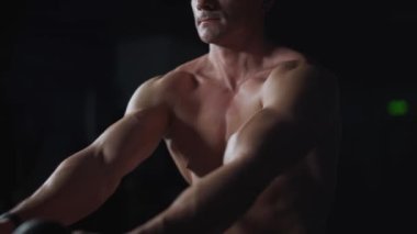 Spor salonundaki adam kürek çekme makinesindeki blokları kaldırıyor, blok aygıtı ve spor aleti eğitimi alıyor, gece antrenmanı, 450 fp..