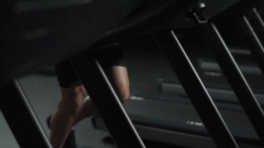 Koşu bandında koşan atletik bir adam, spor salonunda aerobik egzersiz ve dayanıklılık eğitimi, gece eğitimi, 4k ağır çekim.