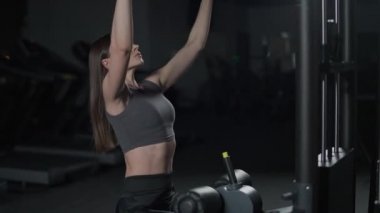 Spor salonunda kadın kaldırma blokları raf makinesinde, blok aygıtı ve spor aletleri üzerinde güç eğitimi, gece eğitimi, 450 fps.