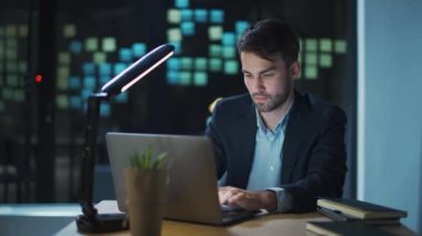 Genç işadamı ofiste bir masada oturur ve dizüstü bilgisayarda çalışır. Yönetici başarılı bir finansal işlem yapar..