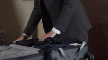 Takım elbiseli bir işadamı kıyafetlerini bavula koyar, iş gezisine çıkar, otel odasının içini temizler..