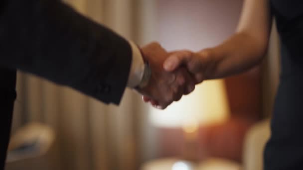 Ein Mann im Anzug, ein Geschäftsmann, der einer Kollegin die Hand schüttelt, ein Händedruck im Hotelzimmer. — Stockvideo