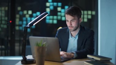 Genç işadamı ofiste bir masada oturur ve dizüstü bilgisayarda çalışır. Yönetici başarılı bir finansal işlem yapar..