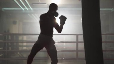 Kickboks, atletik boksör yumruklarını geliştirir, kum torbasını döver, boks salonunda antrenman yapar, ayaklarıyla vurur, sırtını aydınlatır..