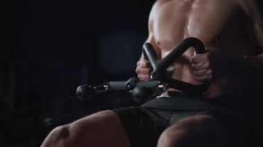 Spor salonundaki erkek sporcu kürek çekme makinesindeki blokları kaldırıyor, blok aleti eğitimi alıyor, gece antrenmanı yapıyor, 450 fp..