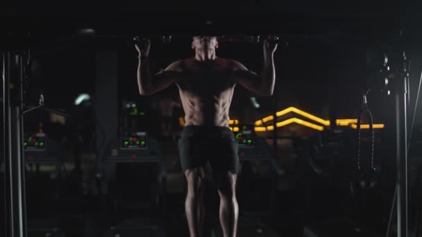 Bienestar, hombre atlético realiza pull-ups en la barra horizontal, entrenamiento de fuerza en el gimnasio por la noche, luz cinematográfica, 4k super cámara lenta. — Vídeos de Stock