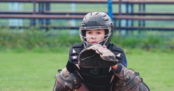 Retrato de un jugador de béisbol niño sobre un fondo borroso, el receptor en equipo de protección atrapa una bola rápida volando al guante, 4k cámara lenta. — Vídeos de Stock