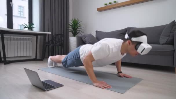 戴著虚拟现实眼镜的人进行锻炼和俯卧撑，运用现代技术进行自我隔离的体育运动. — 图库视频影像